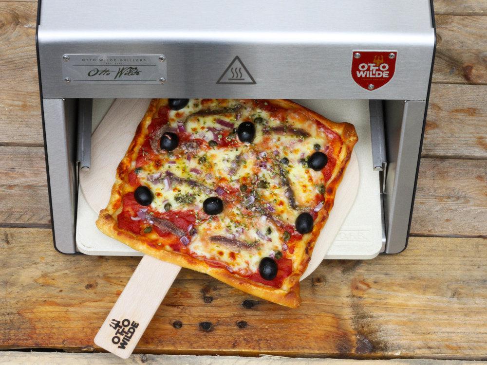 Fertige Pizza auf einer Pizzaschaufel, die aus einem Oberhitzegrill O.F.B. gezogen wird