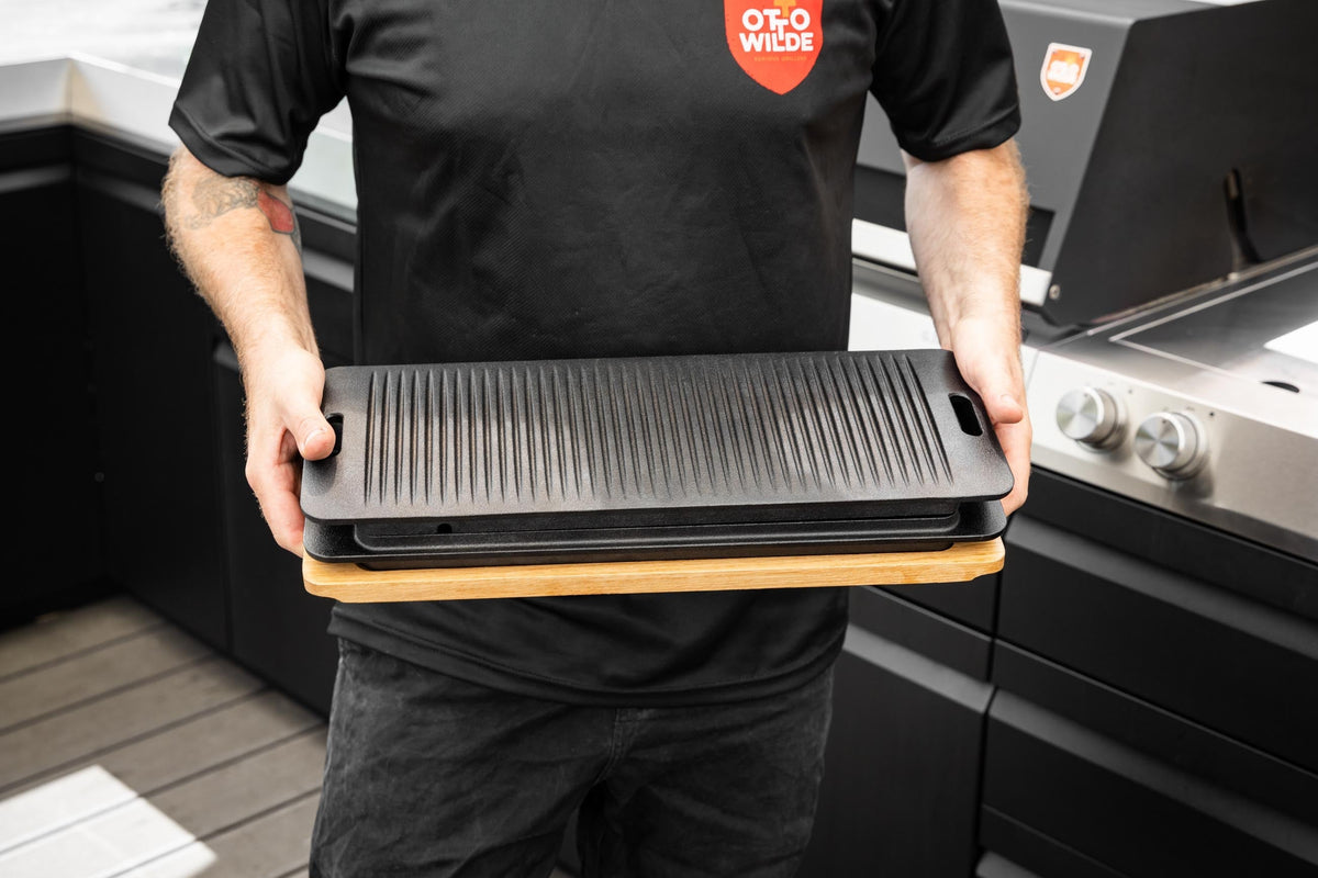 Ein Mann hält eine Gusseiserne Grillplatte auf einem Holzbrett