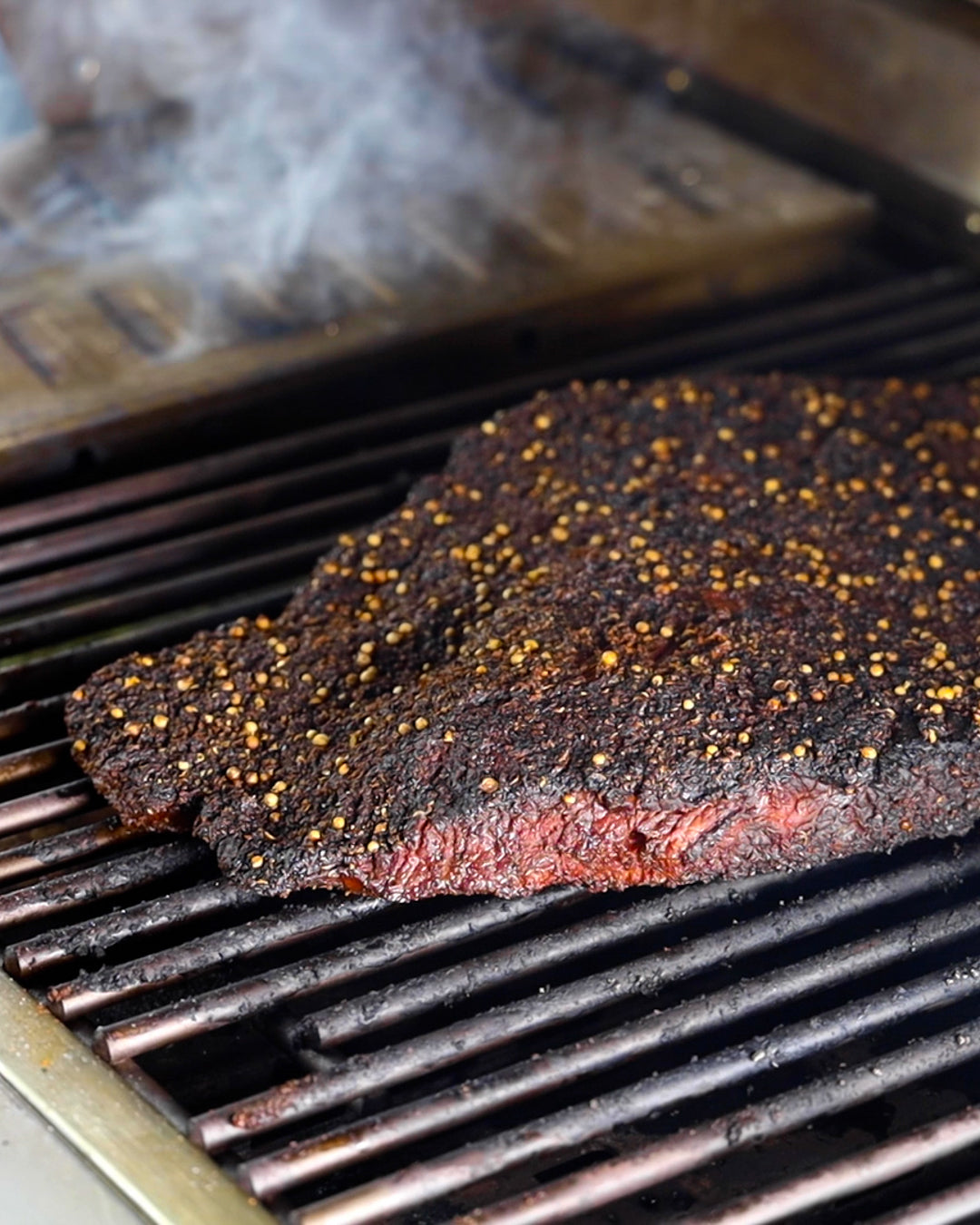 Ein Stück Fleisch mit Rub eingerieben auf dem Grill