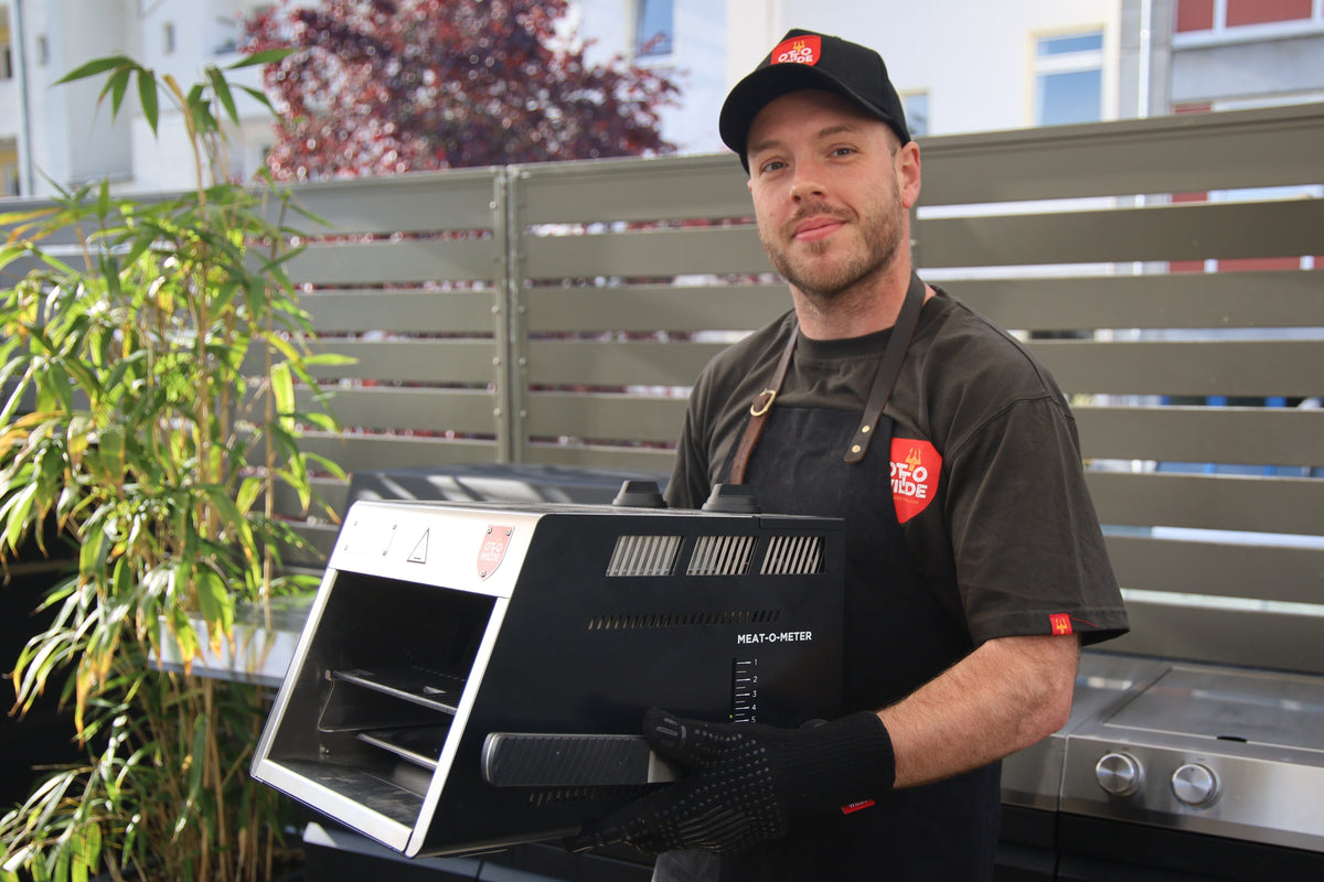 Mann mit Oberhitzegrill O.F.B. vor Outdoor-Küche