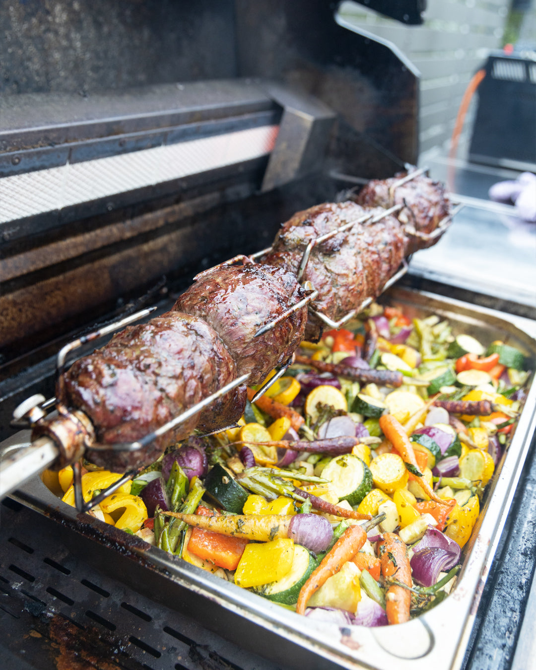 Fleisch auf der Rotisserie vom Gasgrill G32 mit Gemüse