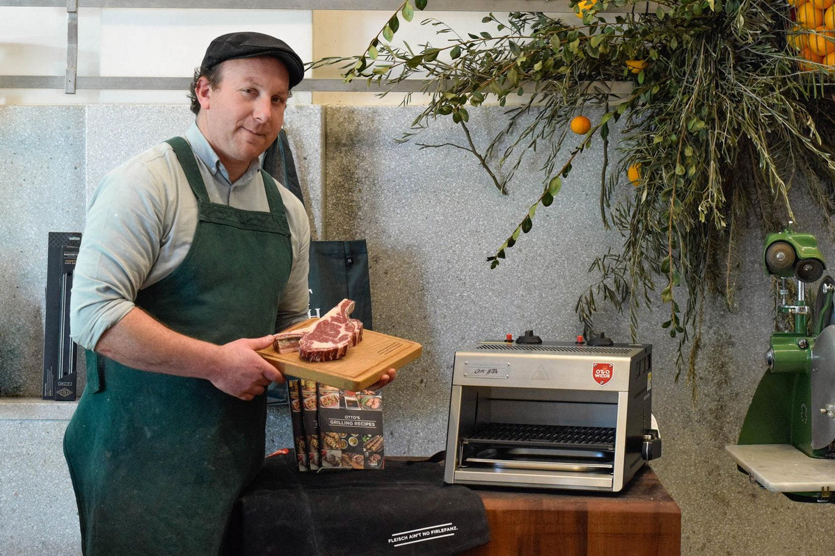 MEATSMITH mit Steak auf einem Holzbrett vor dem Oberhitzegrill O.F.B.